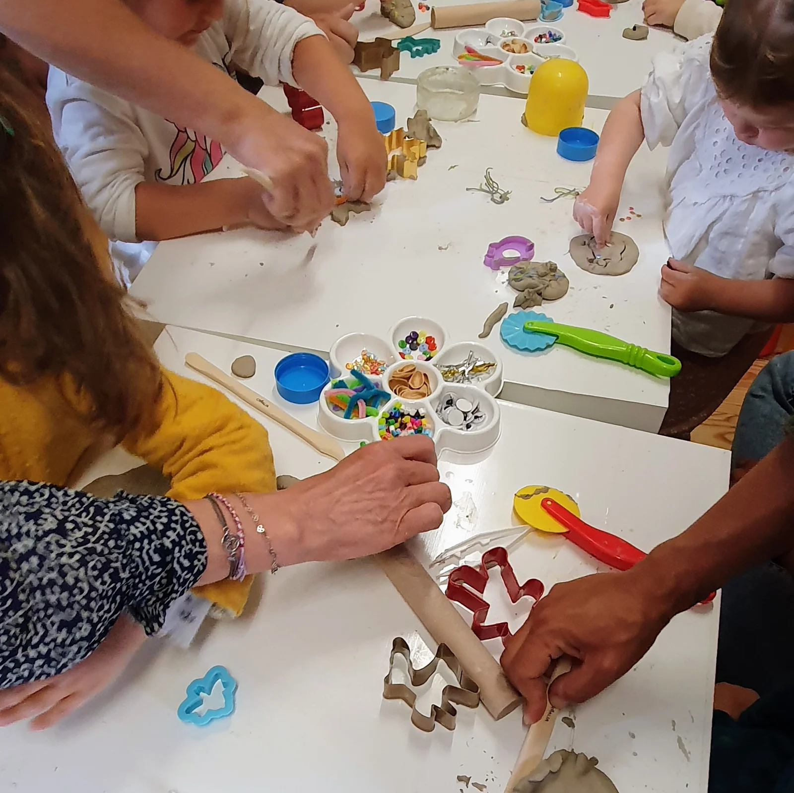 Atelier modelage : mains d'enfants et d'adultes autour des emporte-pièces